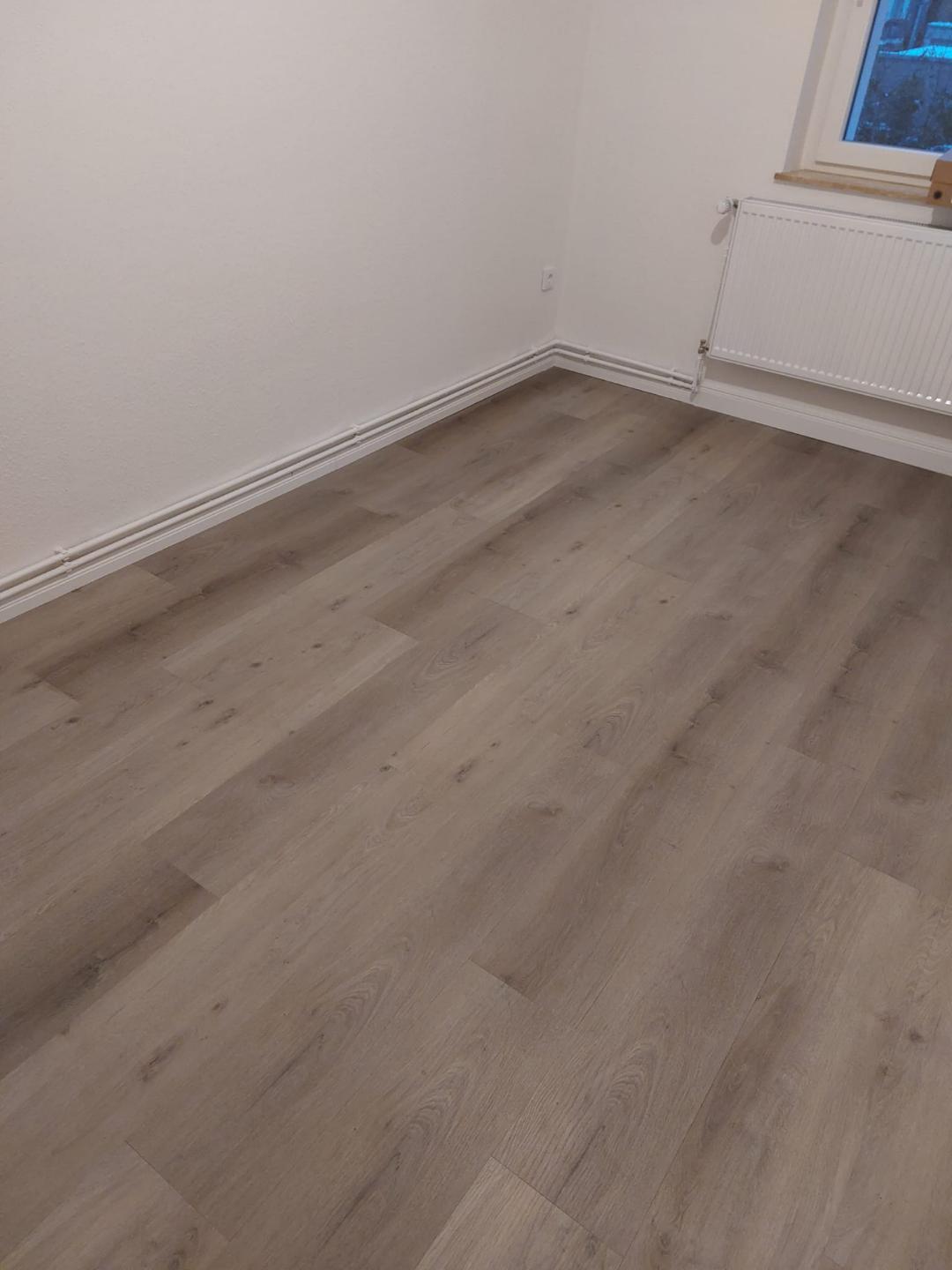 Frisch verlegter Vinylboden in Eichenoptik mit weißen Sockelleisten